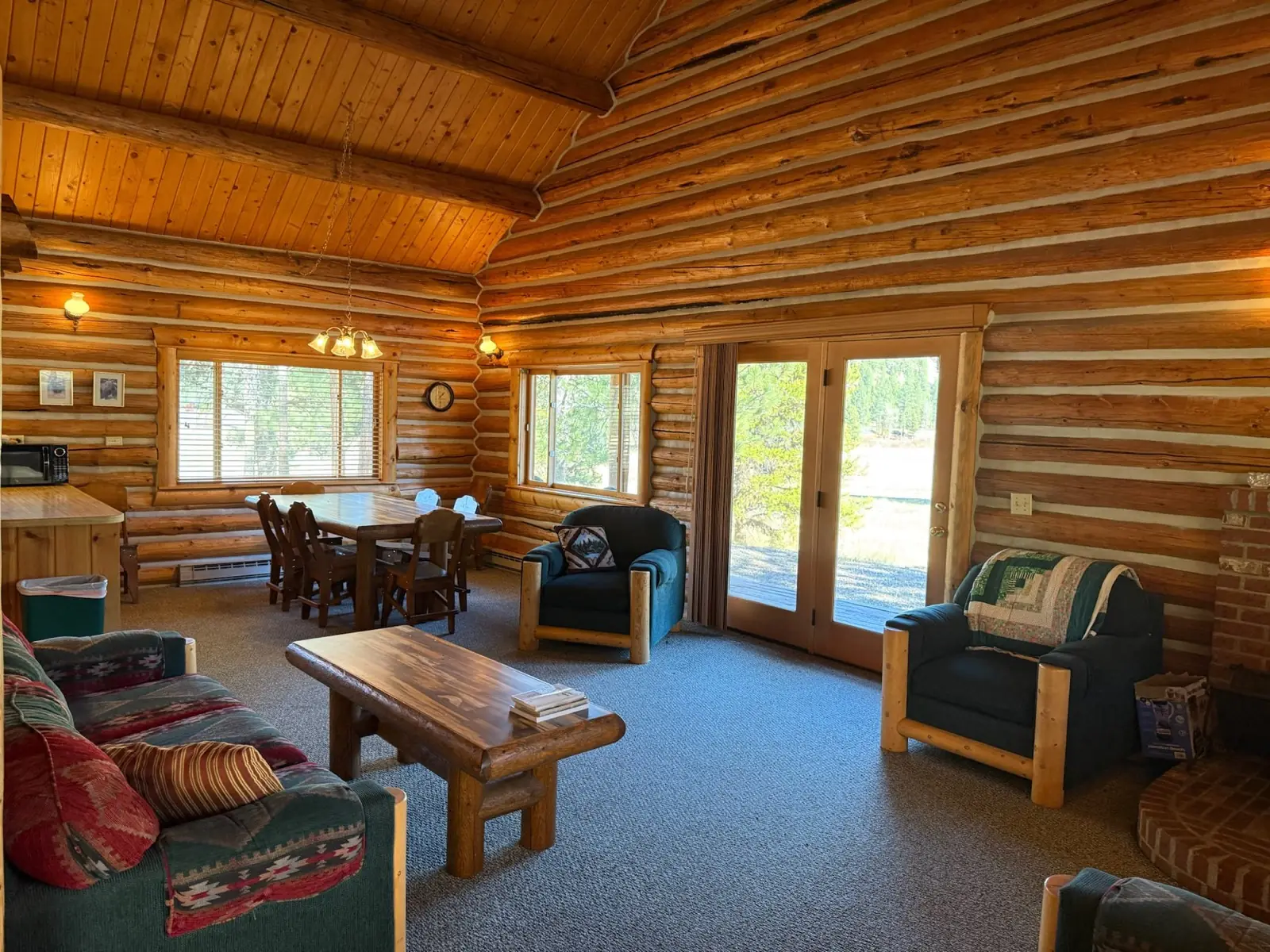 Inside the Cottonwood cabin: a vaulted log living room with a dining table
