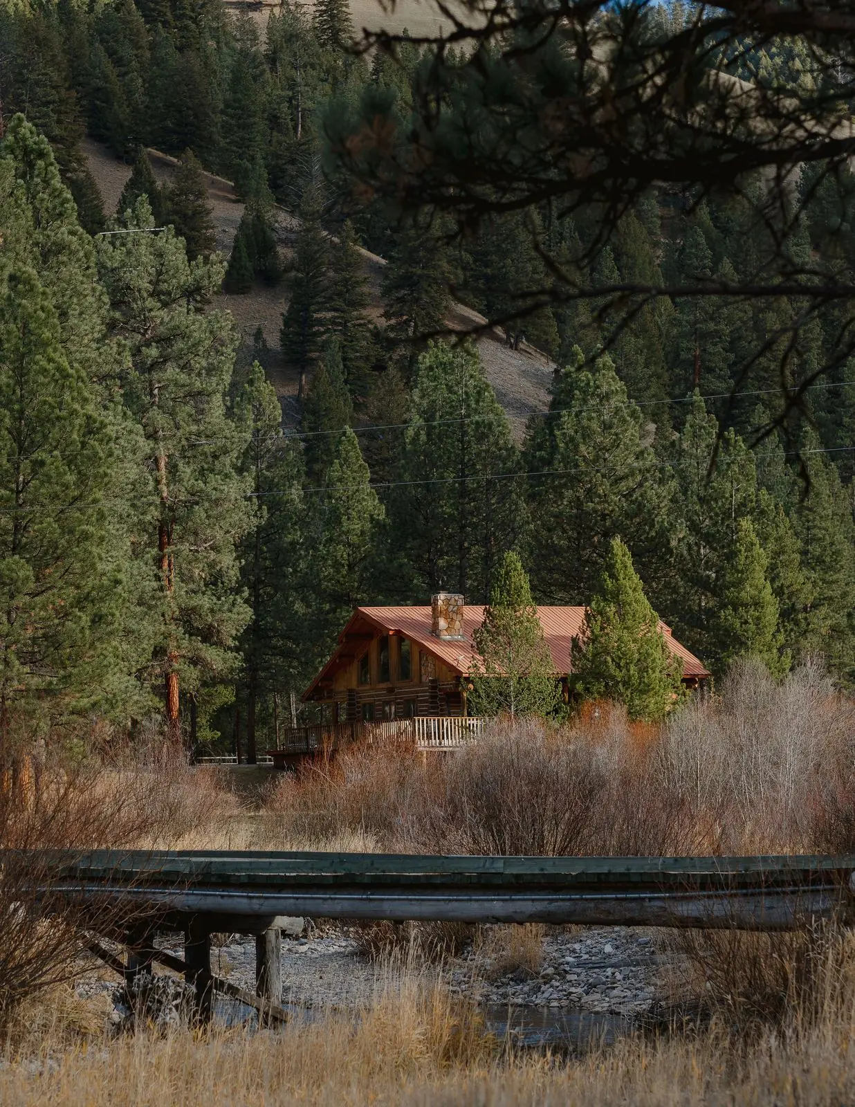 A log cabin tucked among pines beside a stream near Darby, Montana