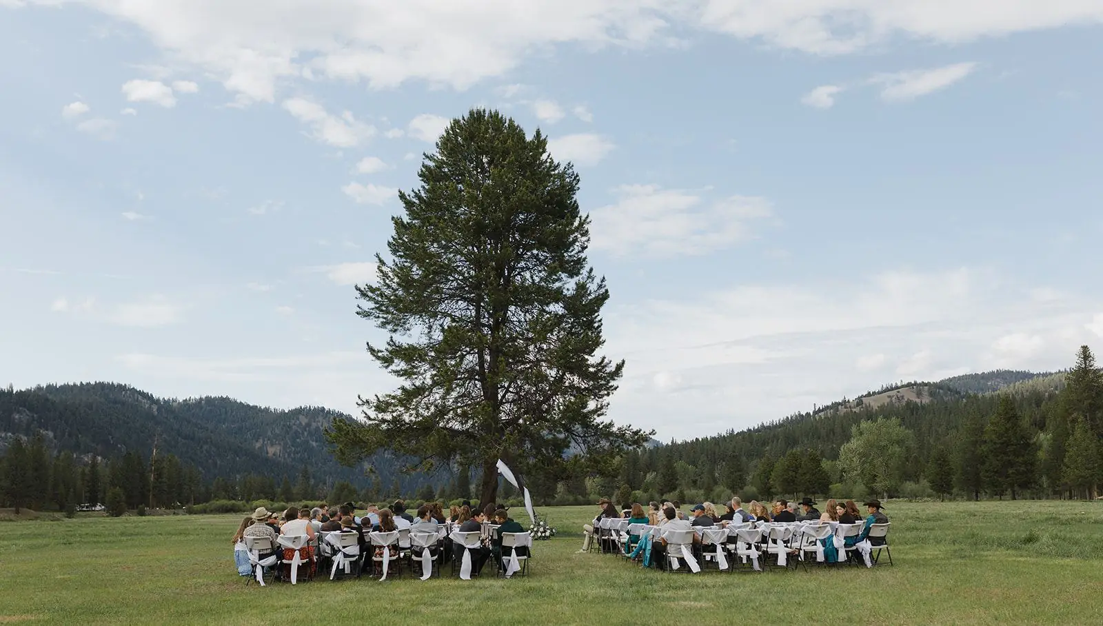 A wide view of an outdoor wedding ceremony in the ranch meadow