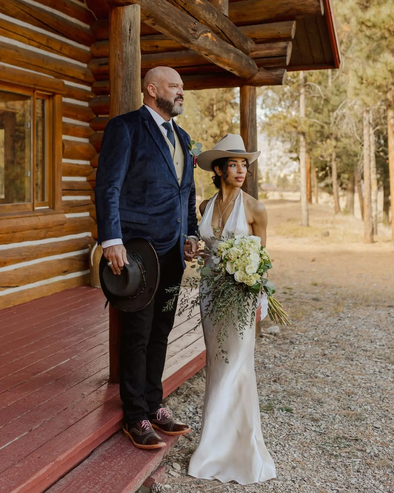 A bride and groom standing together on a log cabin porch at Alta Ranch