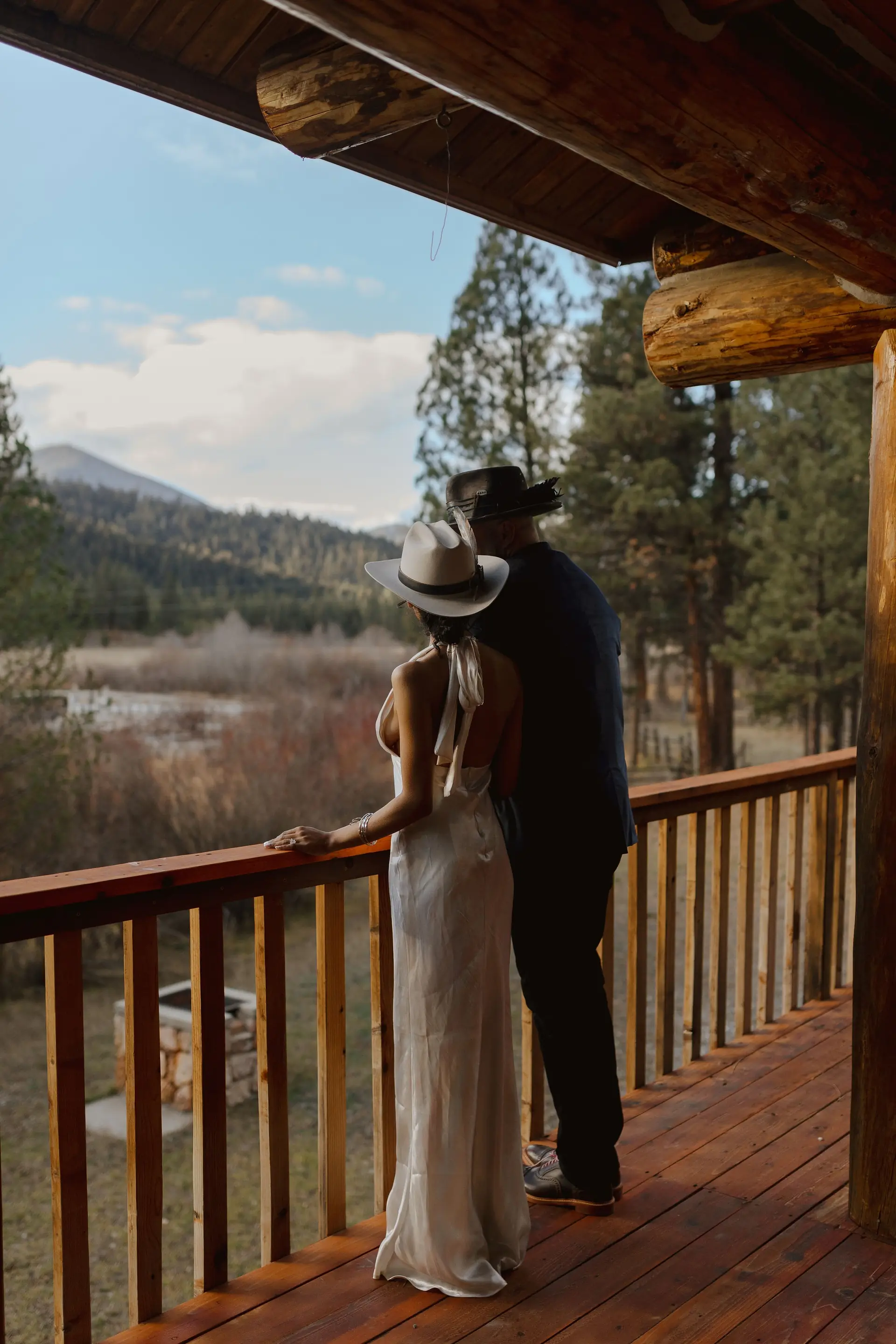 A couple standing together on the lodge deck, looking out across the river valley