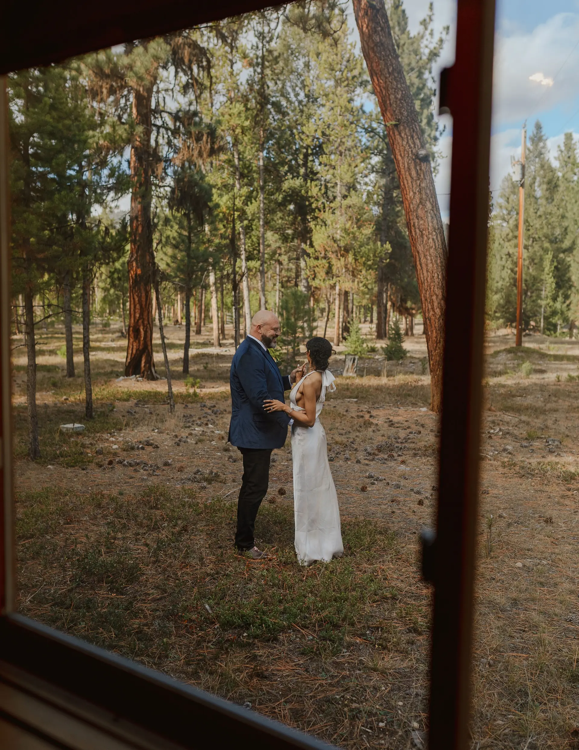 A couple sharing a quiet moment in the pines, framed by a cabin doorway