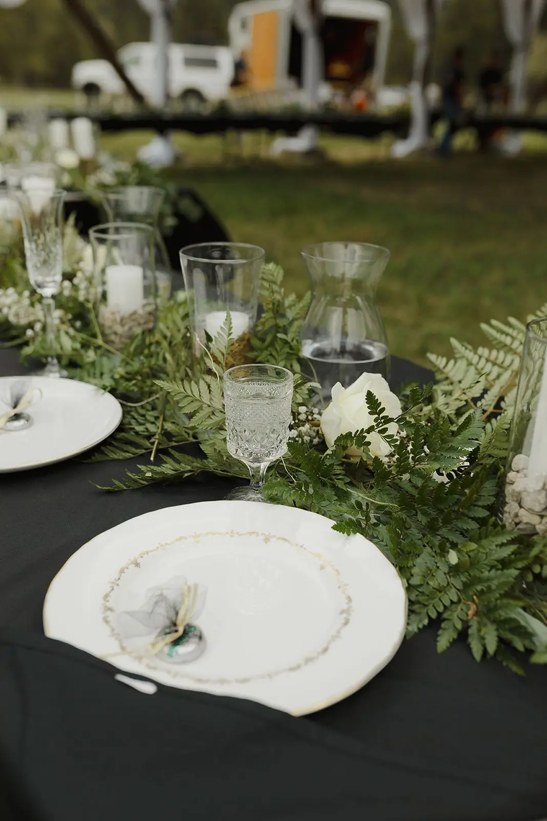A reception table set with greenery and glassware under the hangar at Alta Ranch