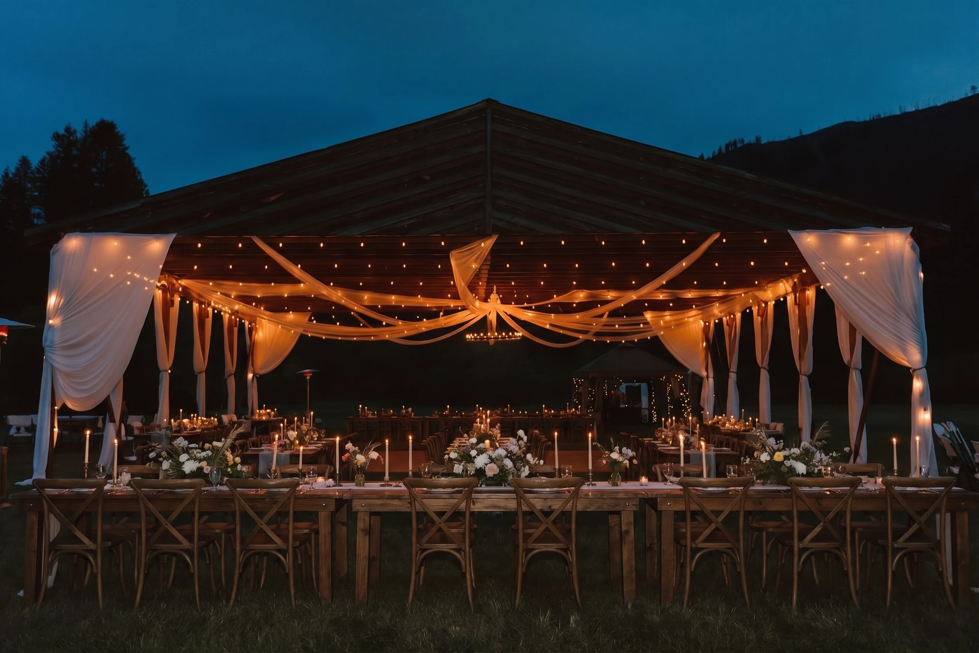 Styling idea: the hangar at blue hour with drapes, string lights and long candlelit tables